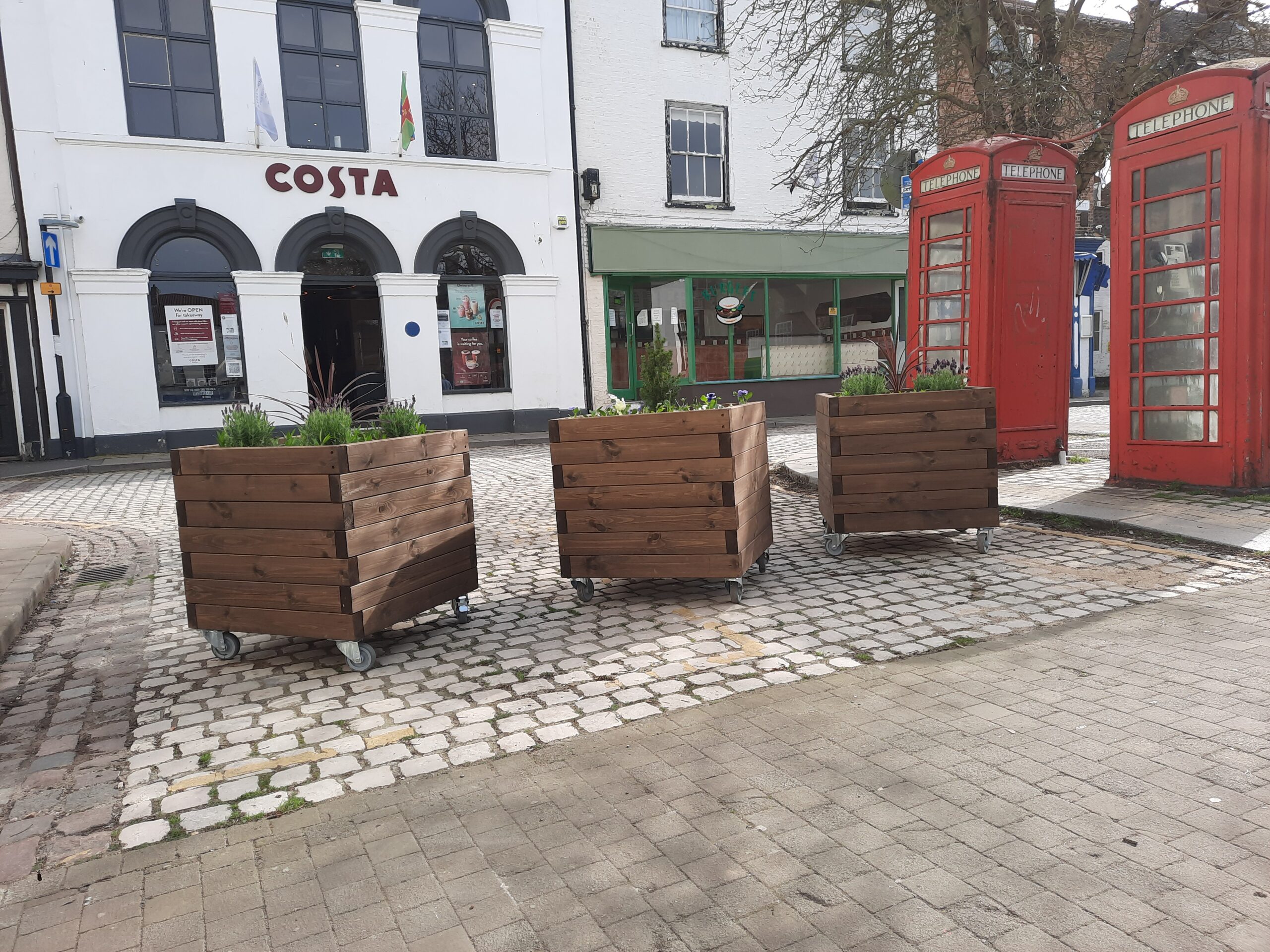 image of planters on the cobbles outside the Post Office on the Market Place Horncastle, showing Costa coffee behind them and the two red telephone boxes to the right.
